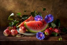 a watermelon and plums on a plate with purple flowers