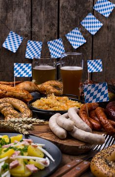 a table topped with lots of food next to beer glasses and plates filled with food