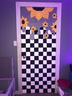 a door decorated with sunflowers and black and white checkerboard, next to a laundry hamper