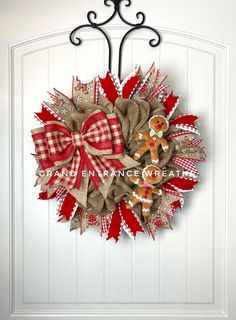 a red and white wreath with two teddy bears on it