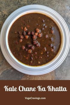 a white bowl filled with chili and beans on top of a stone counter next to a spoon