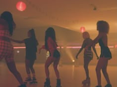 several young women skateboarding in a dimly lit room