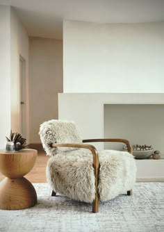 a living room with a chair, table and fire place in the corner on carpeted flooring