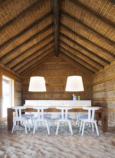 a dining table with four chairs and two lamps on it in the middle of a room