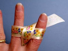 a woman's left hand with a flowered ribbon on it and a gold ring