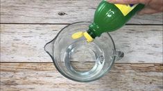 someone is pouring water into a glass bowl with a yellow plastic sippy bottle in it