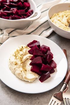 beets and mashed potatoes on a white plate next to bowls of hummus