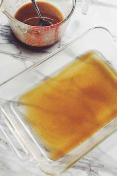 a glass container filled with liquid next to a measuring cup on a marble counter top