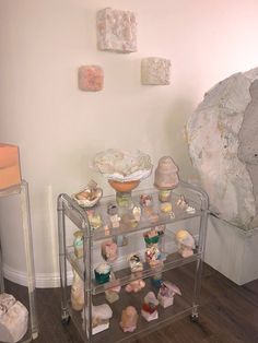 there is a glass shelf with many small objects on it in the corner next to a large rock