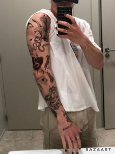 a man taking a selfie with his cell phone in front of him and tattoos on his arm