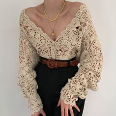 a woman wearing a crochet top and black pants with her hands on her hips