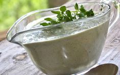 a glass bowl filled with liquid sitting on top of a wooden table next to a spoon