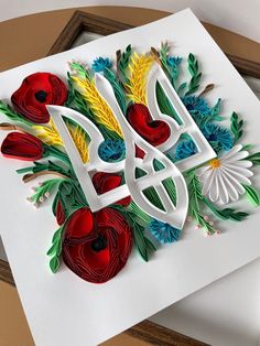 a card with flowers and the letter d is made out of quilled paper on top of a piece of white paper