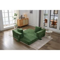 a green couch sitting on top of a hard wood floor next to a white rug