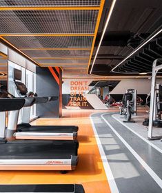 there are many treadmills in the gym with orange and black stripes on them