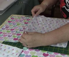 a woman is cutting fabric on top of a quilter's block with scissors