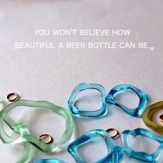 four different colored rings sitting next to each other on top of a white surface with the words you won't believe how beautiful a beer bottle can be