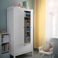 a baby's room with a rocking chair and white cabinet