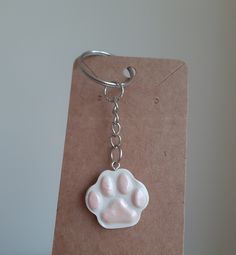 a keychain with a paw print on it sitting on top of a piece of brown paper