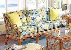 a living room with wicker furniture and large windows overlooking the ocean on a sunny day