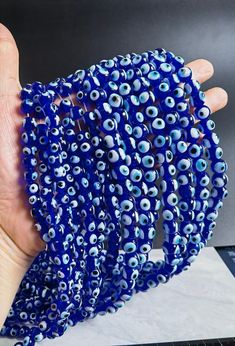 a hand holding a blue beaded bracelet with evil eye beads on it's side