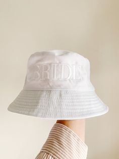 a white brimmed hat with the word bride on it is held up by someone's hand