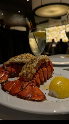 a plate with lobster, egg and lemon on it next to some glasses of wine