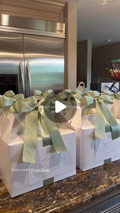 three white boxes with green bows are on the counter in front of a silver refrigerator