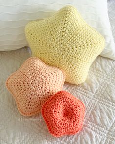 three crocheted pillows sitting on top of a white bed next to each other