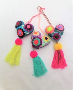 three heart shaped ornaments with tassels and pom - poms on them