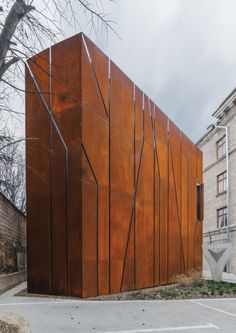 a large metal structure sitting in the middle of a parking lot next to a building