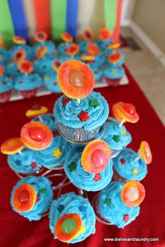 cupcakes with blue frosting and orange icing are on a red tablecloth