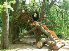 a tree house made out of logs and branches with stairs leading up to the top