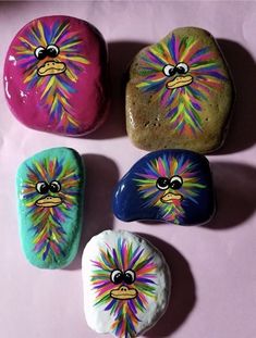 four painted rocks sitting on top of a pink surface