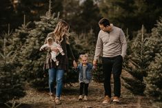 a man, woman and child walking through a christmas tree farm