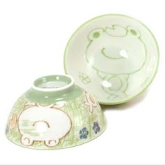 two green and white dishes with animals painted on the side, one has a small bowl in front of it