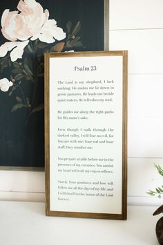 a wooden framed sign sitting on top of a white table next to a vase with flowers