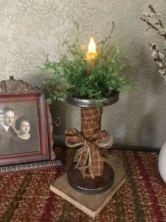 a vase filled with flowers next to an old photo and a candle on top of a table