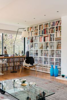 a living room filled with lots of furniture and bookshelves covered in shelves full of books