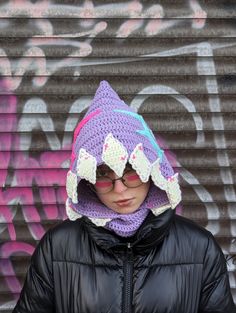 a woman wearing a knitted hat with ears on her head in front of a graffiti covered wall