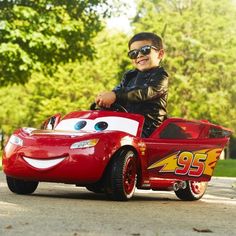 a young boy riding on the back of a red car