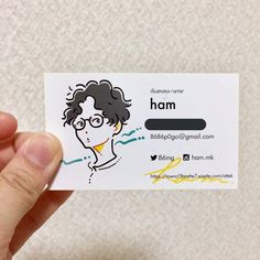 a person holding up a business card with a drawing on it