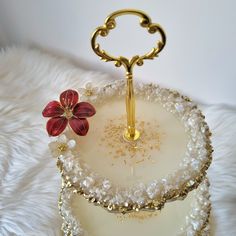 a white and gold tray with a flower on it sitting on a furnishing