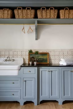 a kitchen with blue cabinets and white sinks in it's center island, along with wicker baskets on the wall