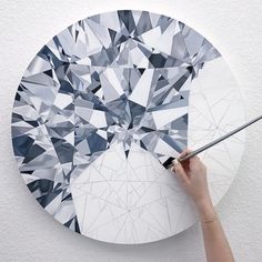 a person using a brush to paint a diamond pattern on a white wall mounted clock