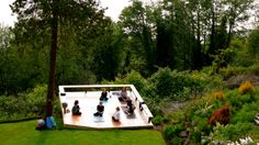 a group of people sitting on top of a wooden platform in the middle of a lush green field