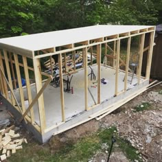 a house being built with wood framing and tools on the ground in front of it