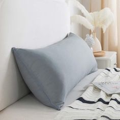 a white bed topped with pillows next to a window