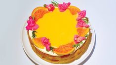 a cake with oranges and pink flowers on it sitting on top of a white plate