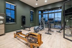 there is a gym with exercise equipment in the room and large windows overlooking the city